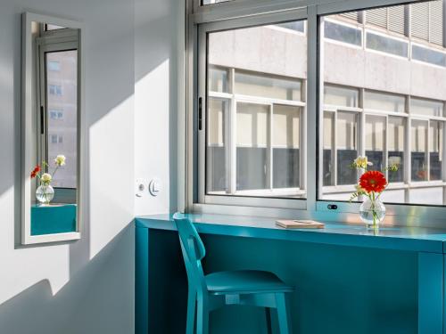 ein blauer Schreibtisch mit einem Stuhl und einem Fenster in der Unterkunft Lisbon Serviced Apartments - Alvalade in Lissabon