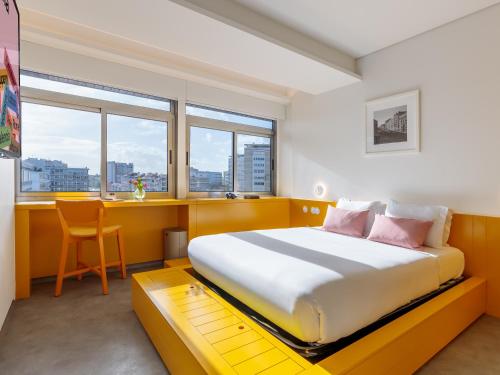 Schlafzimmer mit einem großen Bett, einem Schreibtisch und Fenstern in der Unterkunft Lisbon Serviced Apartments - Alvalade in Lissabon