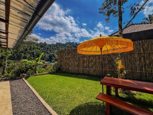 an umbrella sitting on a bench next to a yard at Little Munduk, full private villa in Munduk