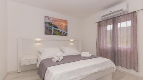 a white bedroom with a bed and a window at Star Hill - Makarska by Villas Guide in Slivno