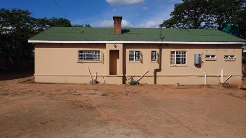 una piccola casa gialla con tetto verde di Cosy Three Bedroom Home a Livingstone