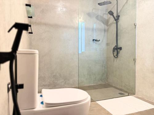 une salle de bains avec toilettes et douche en verre dans l'établissement Bela Ahangama, à Ahangama
