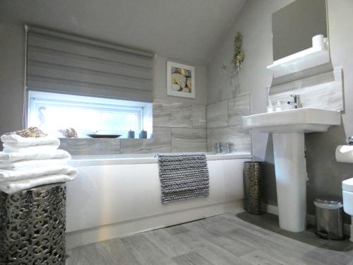 un bagno con vasca e lavandino di The Saddlery Holiday Cottage - Near Wolds And Coast a North Thoresby