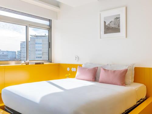 a bedroom with a bed with pink pillows and a window at LSA Alvalade by Numa in Lisbon