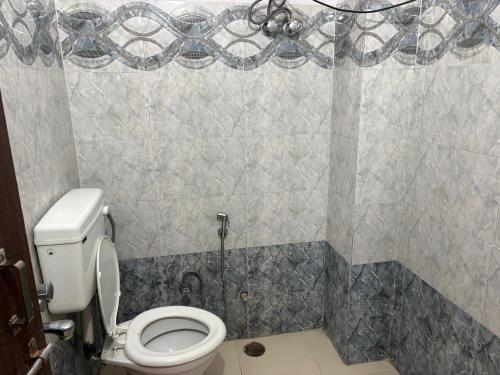 a bathroom with a toilet and a tiled wall at Hotel Mohan in Agra