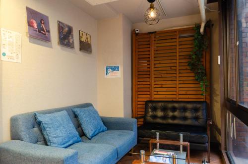 ein Wohnzimmer mit einem blauen Sofa und einem Ledersessel in der Unterkunft bnb+ Secret Base Mejiro in Tokio