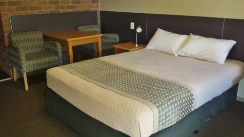 a bedroom with a bed and a chair and a table at Cattleman's Rest Motor Inn in Charters Towers
