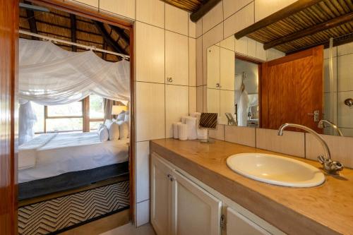 een badkamer met een wastafel en een slaapkamer met een bed bij Karongwe - Kuname Safari Lodge in Hoedspruit