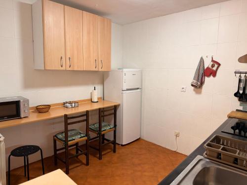 eine Küche mit einem Kühlschrank und einem Tisch mit Stühlen in der Unterkunft Casa Escalones in Villalba