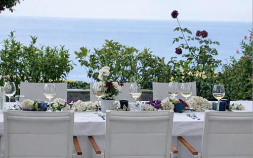 einen Tisch mit weißen Stühlen und Weingläsern in der Unterkunft MEDITERRANEAN SEASONS, VILLA MEDITERRANEA Taormina, Private Pool & Sea View in Taormina
