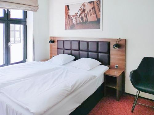 sypialnia z dużym łóżkiem i krzesłem w obiekcie Dancenter Hotel Jomfru Ane w Aalborgu