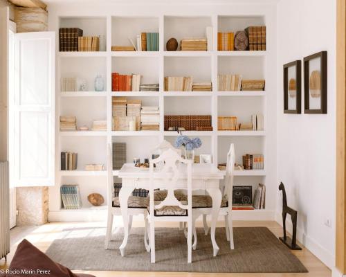a white dining room with a table and bookshelves at A galería do san Ramón in Villalba