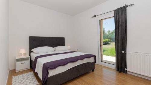 ein Schlafzimmer mit einem Bett und einem großen Fenster in der Unterkunft Villa Tea - Makarska by Villas Guide in Gornji Vinjani