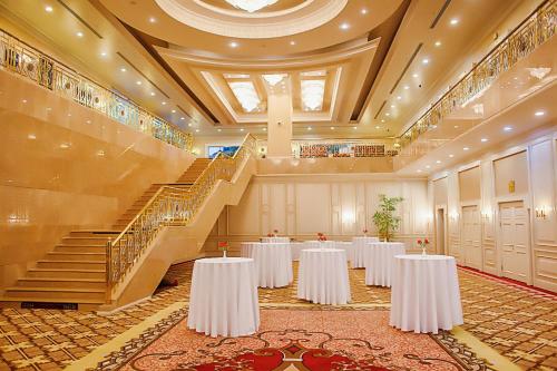 a banquet hall with white tables and stairs at Rixos President Hotel Astana in Astana