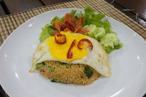 a plate of food with an egg and rice and vegetables at Wijaya Guesthouse in Canggu
