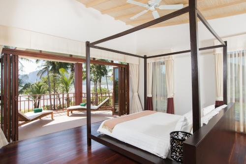 1 dormitorio con cama con dosel y balcón en Amatapura Beachfront Villa 1, SHA Certified, en Ao Nam Mao