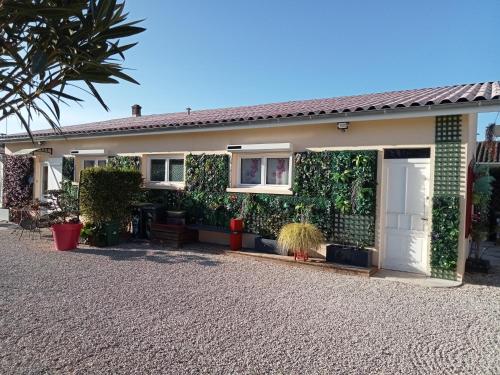 een huis met een muur bedekt met planten bij une pause quelque part au jardin des érables et des niwakis in Saint-Médard-de-Guizières