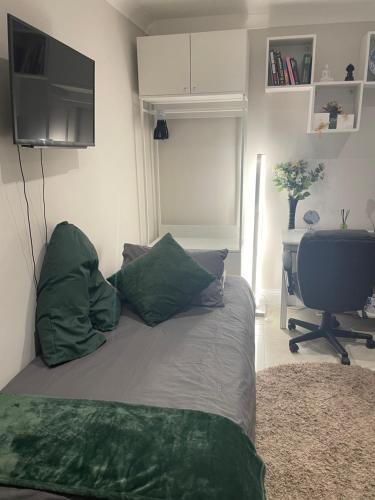 een slaapkamer met een bed met groene kussens en een bureau bij Costa del Pinner in Northwood