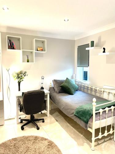 een slaapkamer met een bed, een bureau en een stoel bij Costa del Pinner in Northwood