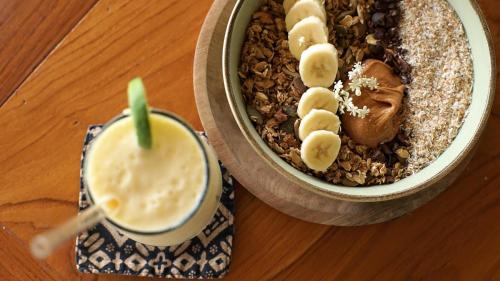 eine Schüssel Haferflocken mit Bananenscheiben und ein Getränk in der Unterkunft Aman Amed Lima 3BR Villa w Panoramic Ocean Views in Amed