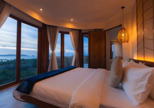 - une chambre avec un grand lit et de grandes fenêtres dans l'établissement Atalaya Resort El Nido, à El Nido