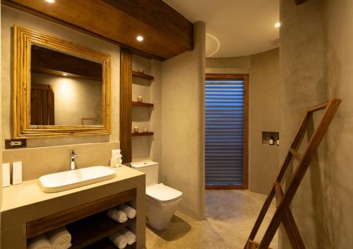 une salle de bains avec lavabo, toilettes et miroir dans l'établissement Atalaya Resort El Nido, à El Nido