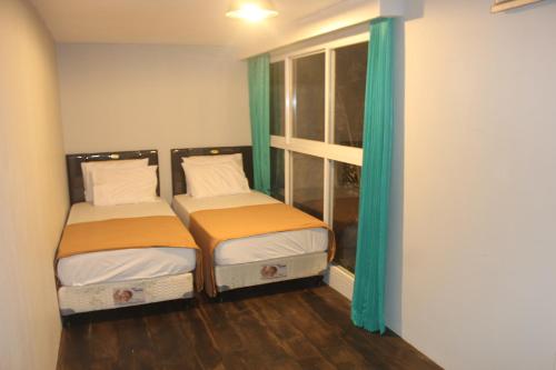 two beds in a room with green curtains at Kubu Container in Uluwatu