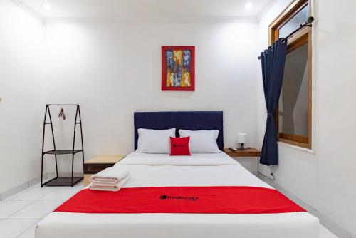 een slaapkamer met een groot bed met een rode deken bij RedDoorz Plus near Universitas Maranatha Bandung 2 in Bandung
