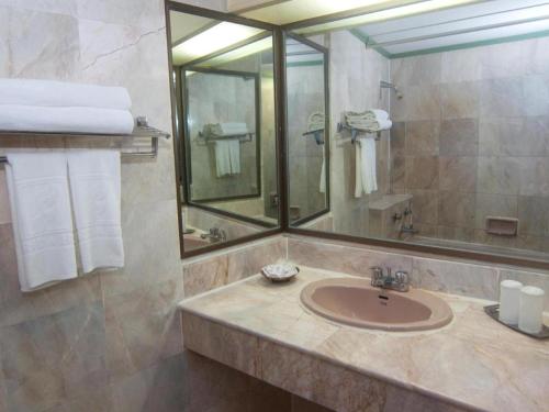 ein Badezimmer mit Waschbecken, Spiegel und Handtüchern in der Unterkunft Florida Hotel in Hat Yai