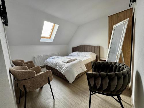 a bedroom with a bed and a mirror and a chair at Tudor's Rooms in Mediaş