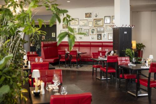 a restaurant with red chairs and tables in a room at ARCOTEL Kaiserwasser Wien in Vienna