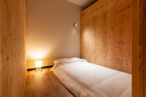 a bedroom with a bed with a wooden wall at くにまるイン in Kyotango
