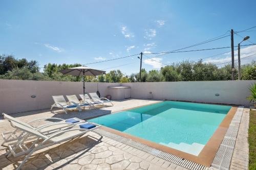 a swimming pool with chairs and an umbrella on a patio at Villa Anastasis in Halikounas
