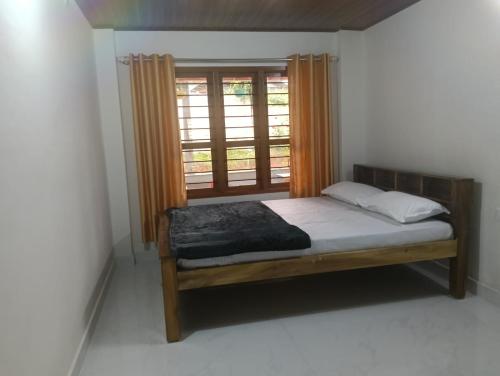 a bedroom with a bed and a window at Anurastays in Mudigere