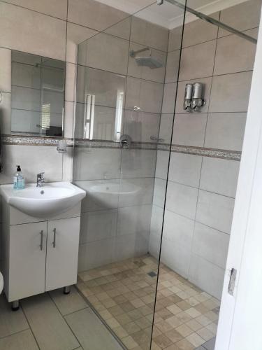 a bathroom with a sink and a glass shower at The Terrace Guest House in Roodepoort