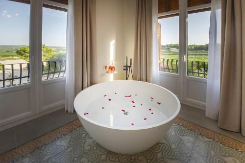 - une baignoire blanche dans une chambre avec fenêtres dans l'établissement Habitación Rossinyol, à Castellví de la Marca