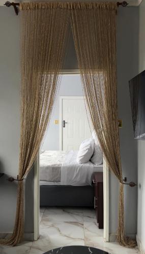 a bedroom with a bed with curtains and a window at Uduak Lodge in Harare