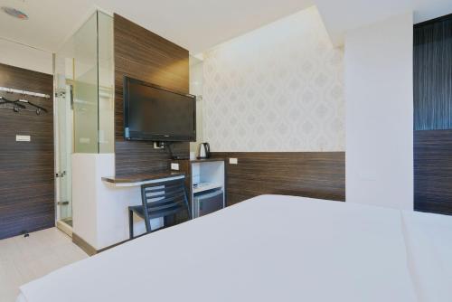 a room with a tv and a desk with a chair at Wecan Hotel in Kaohsiung