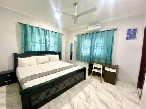 Schlafzimmer mit einem Bett und einem Schreibtisch sowie blauen Vorhängen in der Unterkunft Happy Home in Weija