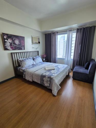 a bedroom with a bed and a chair and a window at 8 Adriatico Condominium 1BR in Sampong