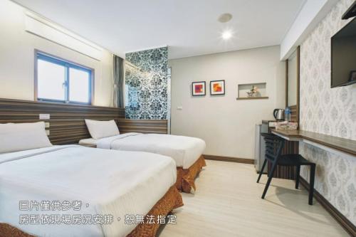 a hotel room with two beds and a television at Wecan Hotel in Kaohsiung
