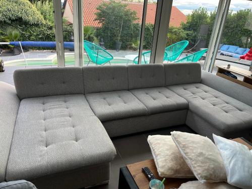 een grijze bank in een kamer met een groot raam bij Villa Zena in Saint-Bonnet-de-Mure