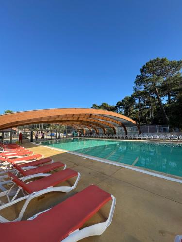 een zwembad met ligstoelen en een stadion bij Chez "Greg et ilhem" in Lège-Cap-Ferret