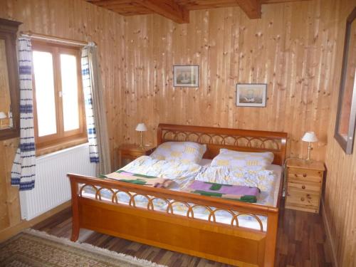 ein Schlafzimmer mit einem Bett mit einer Holzwand in der Unterkunft Naturpark Ferienhaus in Szalafő