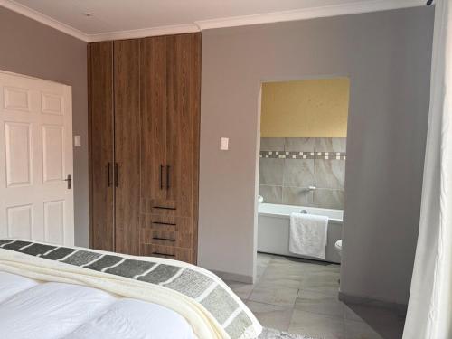 a bedroom with a bed and a bathroom with a tub at Cozzy home in Polokwane