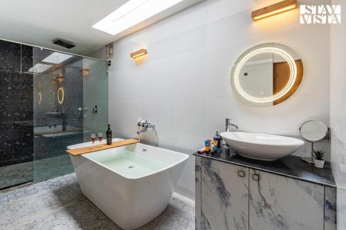 een badkamer met een bad, een wastafel en een spiegel bij StayVista at Jims Farmstay with Pool, Pet-friendly in Halgūr