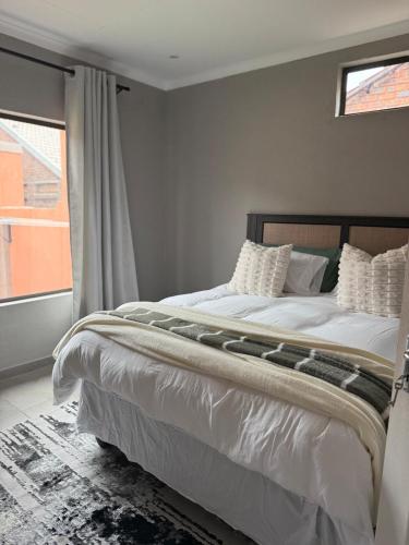 a bedroom with a bed with white sheets and a window at Cozzy home in Polokwane