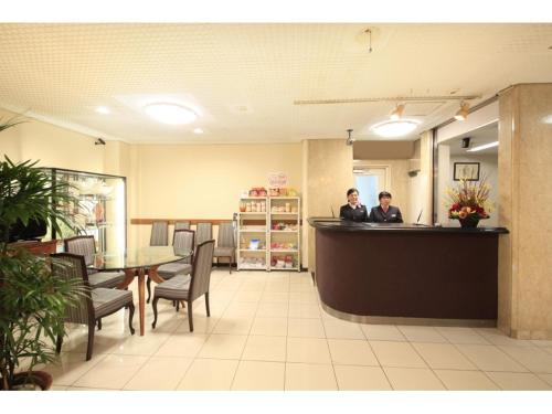 two people sitting at a counter in a restaurant at Chofu Urban Hotel in Chofu