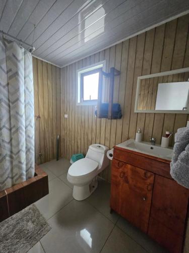 a bathroom with a toilet and a sink and a window at Loft playaBlanca in Coronel
