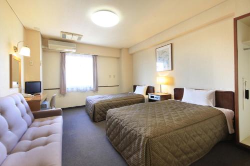 a hotel room with two beds and a television at Chofu Urban Hotel in Chofu